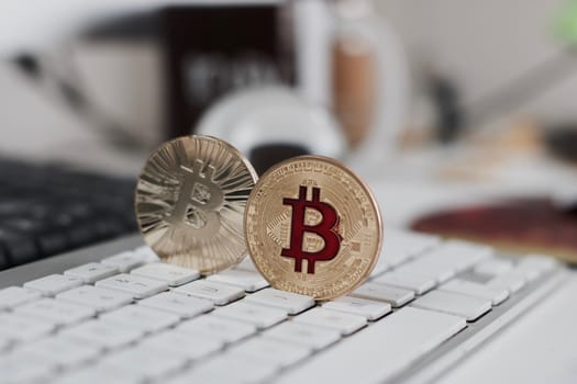 Digital currency physical metal bitcoin coin on the white keyboard near glass ball.