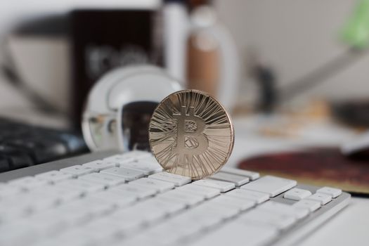 Digital currency physical metal bitcoin coin on the white keyboard near glass ball.