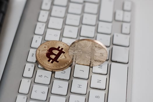 Digital currency physical metal bitcoin coin on the white keyboard near glass ball.