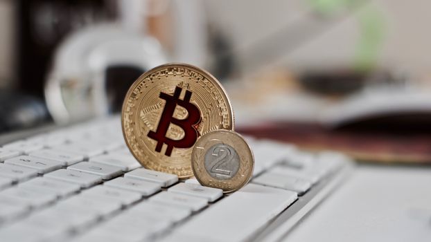 Digital currency physical metal bitcoin coin on the white keyboard near glass ball.
