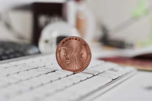 Digital currency physical metal bitcoin coin on the white keyboard near glass ball.