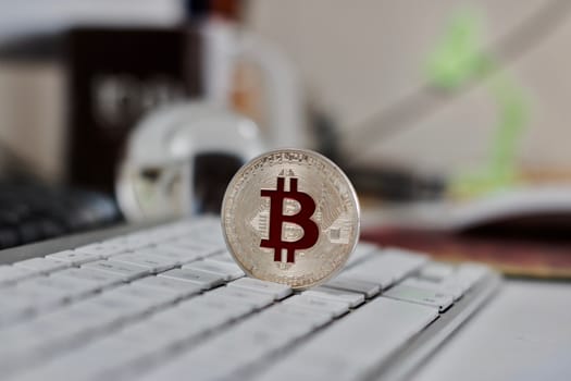 Digital currency physical metal bitcoin coin on the white keyboard near glass ball.