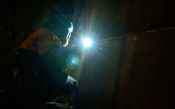 Woman worker welding  inside of shipyard