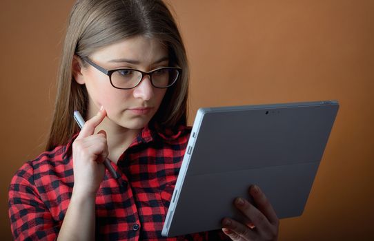 young teenage girl thinking with a tablet