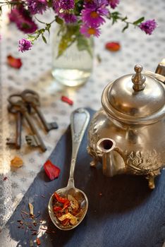 Dry tea leaves on spoon on ardesia plate