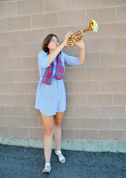 Female jazz trumpet player blowing her horn outside.