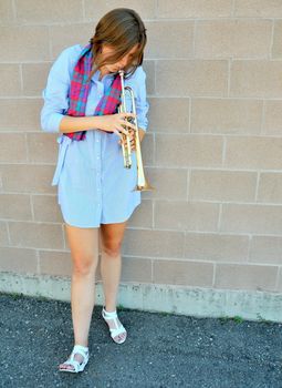 Female jazz trumpet player blowing her horn outside.