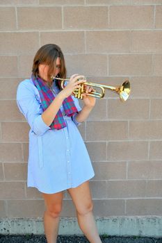 Female jazz trumpet player blowing her horn outside.