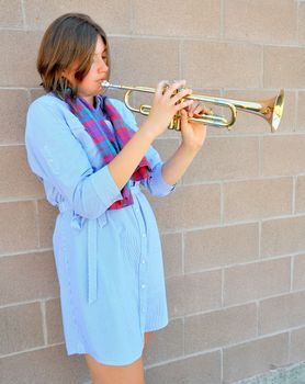 Female jazz trumpet player blowing her horn outside.