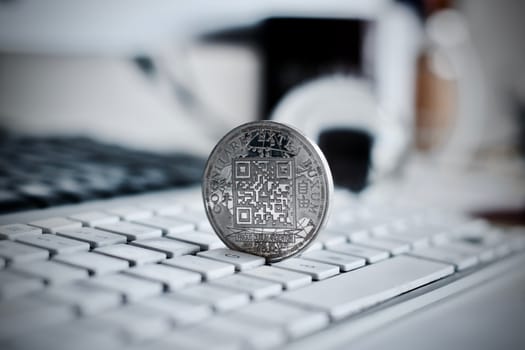 Digital currency physical metal bitcoin coin on the white keyboard near glass ball.