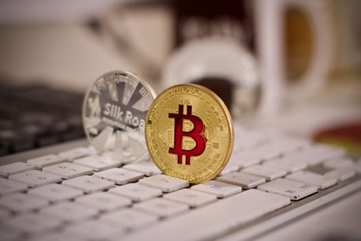 Digital currency physical metal bitcoin coin on the white keyboard near glass ball.