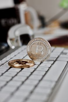 Digital currency physical metal bitcoin coin on the white keyboard near glass ball.