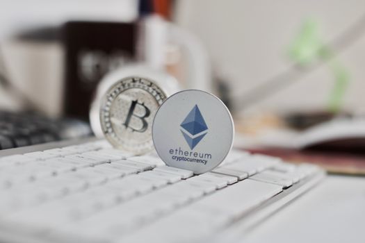 Digital currency physical metal bitcoin coin on the white keyboard near glass ball.