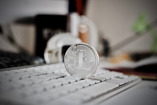 Digital currency physical litecoin coin on the white keyboard. Computer concept.
