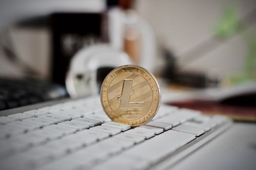 Digital currency physical litecoin coin on the white keyboard. Computer concept.