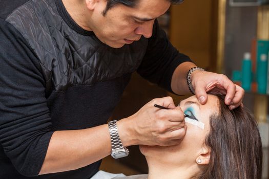 Make up artist creating cat eyes on a white woman