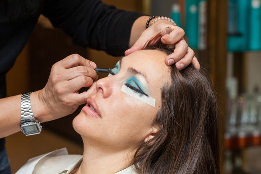 Make up artist creating cat eyes on a white woman