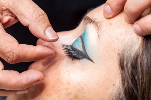 Close up of a makeup artist applying the false eyelashes to a woman