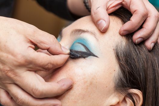 Close up of a makeup artist applying the false eyelashes to a woman