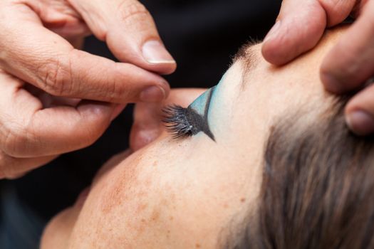 Close up of a makeup artist applying the false eyelashes to a woman