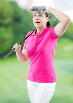 Surprised woman golfer looking where the ball flew away on a background of golf courses