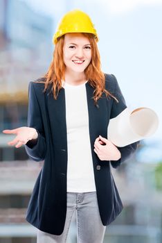 Vertical portrait of a senior architect woman with drawings in a yellow helmet