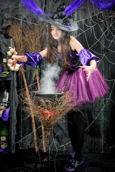 A young witch in a beautiful dress is cooking a love potion