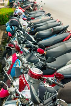 moped parked at the pavement in a row in Thailand