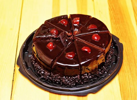 Delicious chocolate cake sliced in portions with fresh cherries.