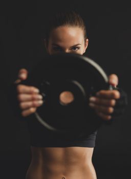 Shot of a beautiful young woman in a workout gear lifting weights