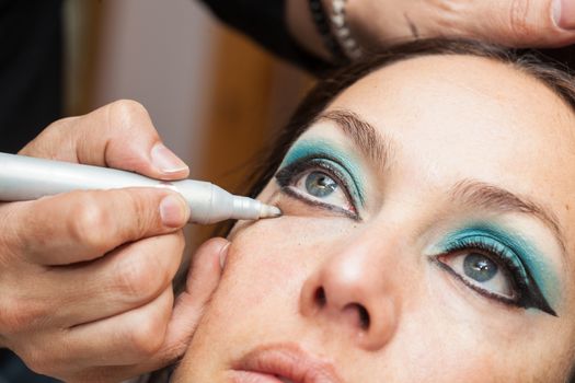 Makeup artist cleaning and giving the final touches to cat eyes makeup