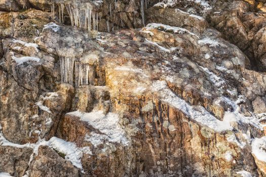 Many small icicles on a stone wall