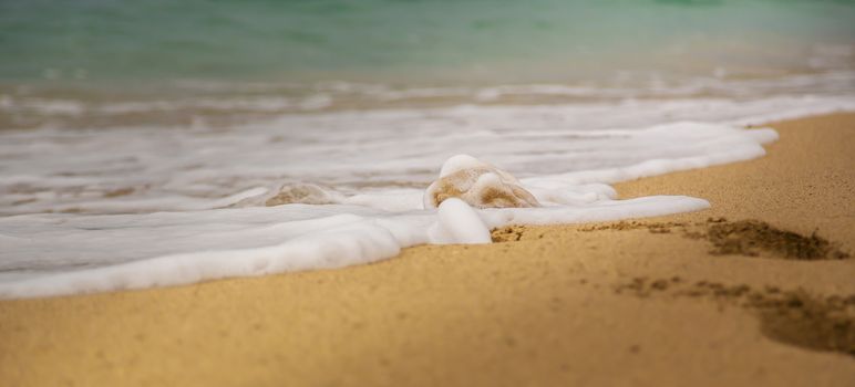 Little wave on a sand beach with traces in the sand