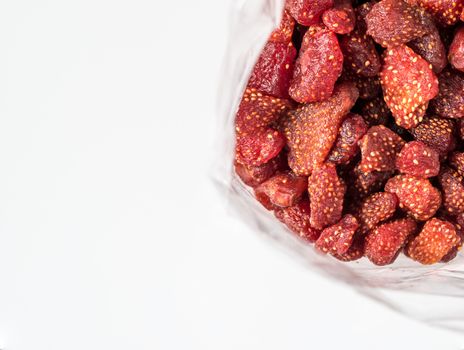 Closeup dried strawberry bake with honey in plastic bag on white background