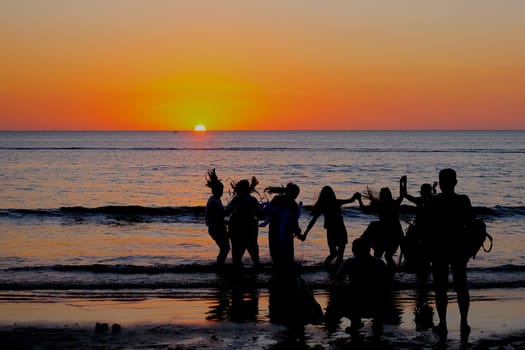 A group of people are enjoying the beautiful sunset view at the beach.