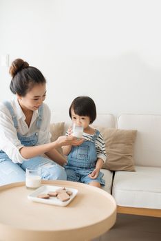 Happy family of asian mom is drinking milk with her cute daughter in the morning at home