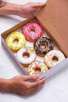 Colored donuts with glaze. Assorted doughnuts with different fillings in the box 