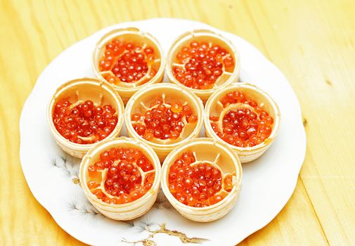 Waffle tartlets with caviar of salmon fish on a kitchen plate.