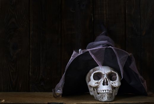 Human skull with magician hat at the wooden wall