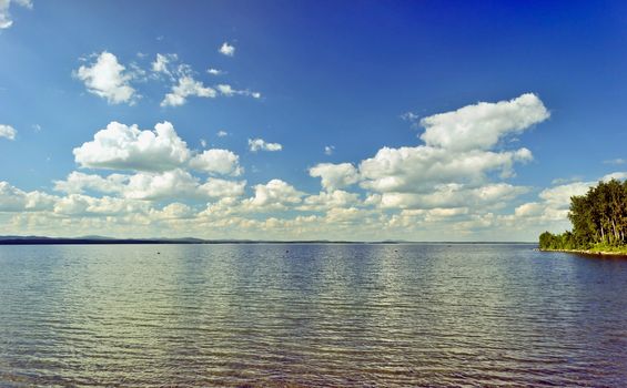 quiet lake Uvildy early in the morning, clear water, clear bottom, South Ural, in the distance are seen the Ural mountains