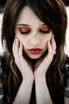 Young lady with beautiful red lipstick and dark red closed eyes.
