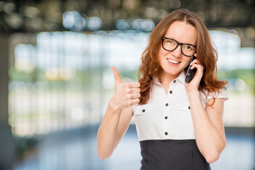 Happy successful businesswoman with phone posing in the office