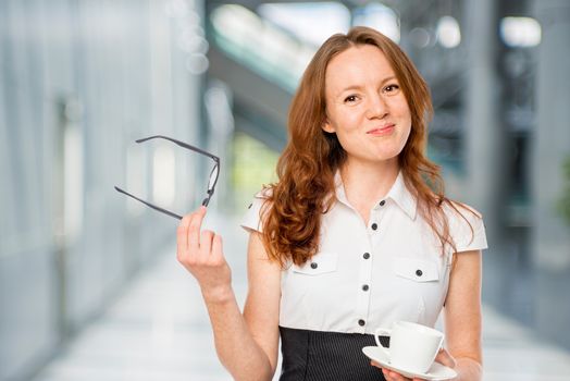 slender young secretary with glasses and coffee in the office