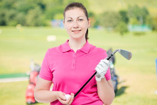 woman with a stick and a ball for golf in the studio on a background of golf courses