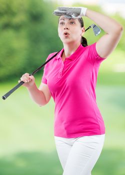 athlete woman watching the ball flight path of golf on a background of golf courses