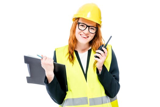 A young woman foreman with glasses and a yellow helmet with a walkie-talkie isolated