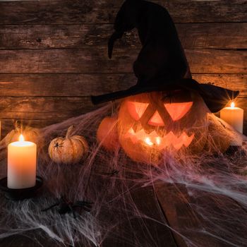 Jack O Lantern Halloween pumpkin with witches hat, spiders on web and burning candles