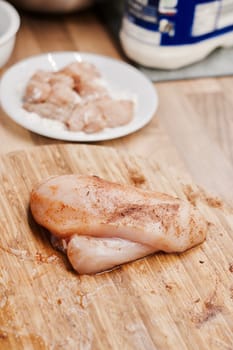 Fresh chicken meat on the wooden board in the kitchen. Home cooking concept.