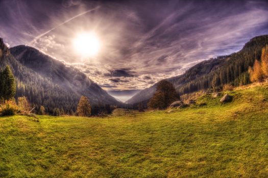 View from a mountain in austria with dramatic sky and sun