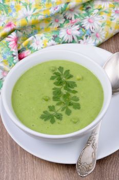 A plate of soup puree of green peas with parsley on a table